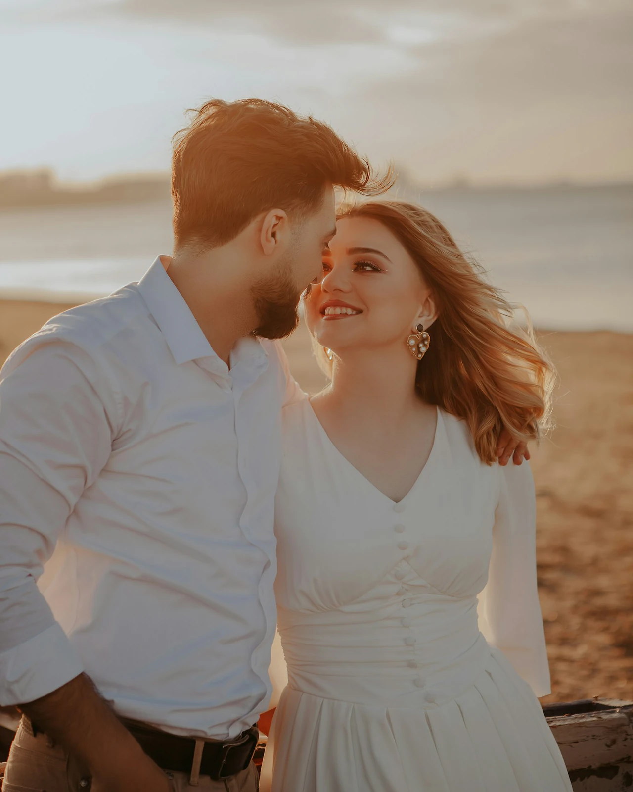 Couple standing together on a beach in warm golden hour light