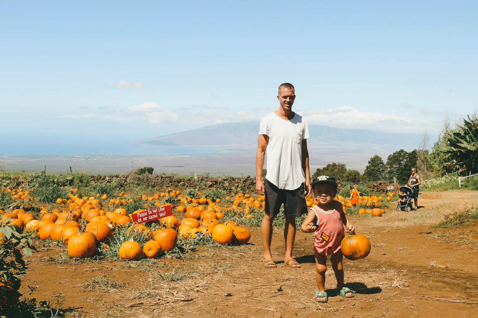 Parent and child posing together in front of pumpkins at a fall pumpkin patch