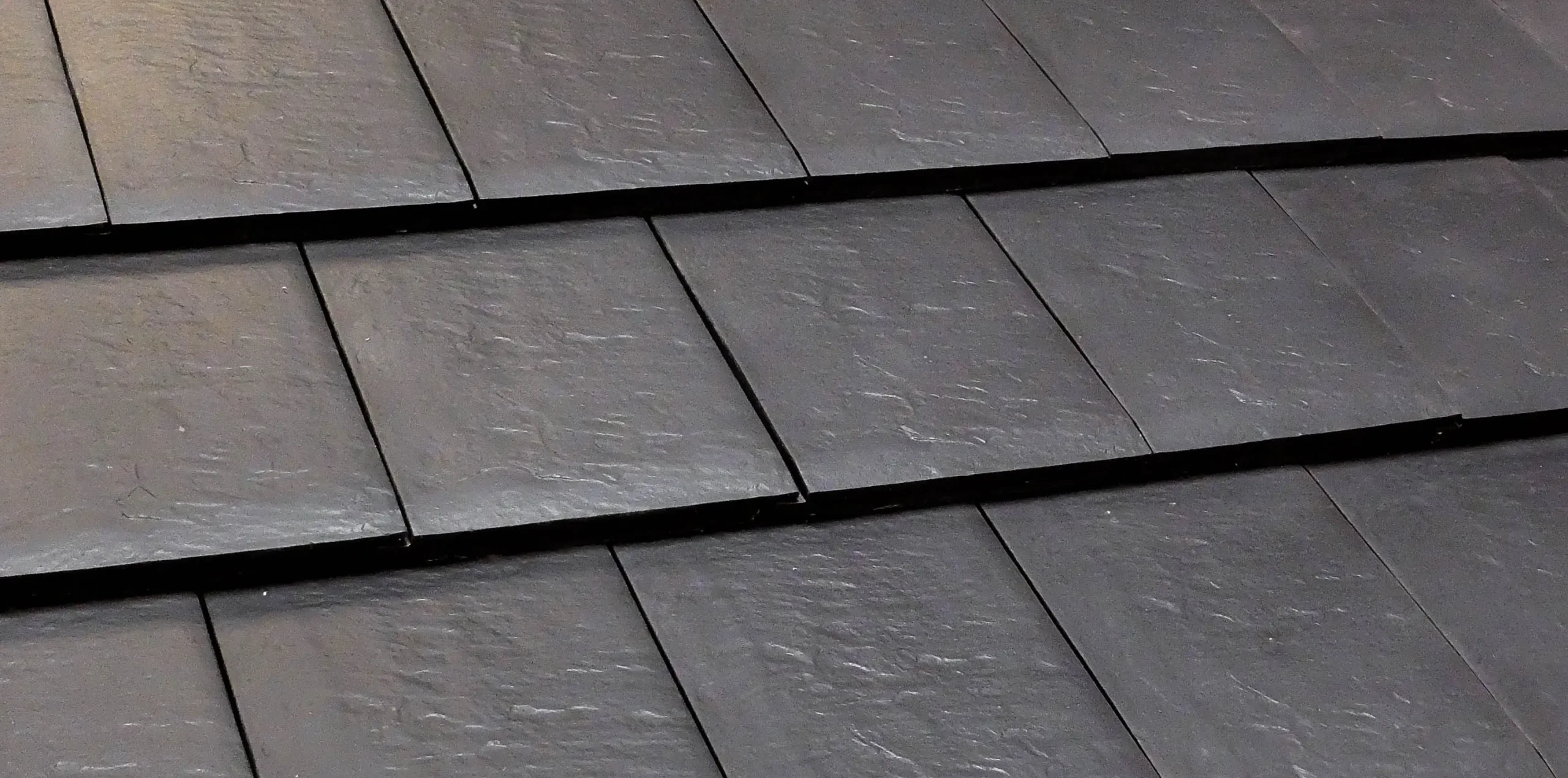 Close-up of black slate roof tiles arranged in overlapping rows Black slate roof tiles overlapping rows