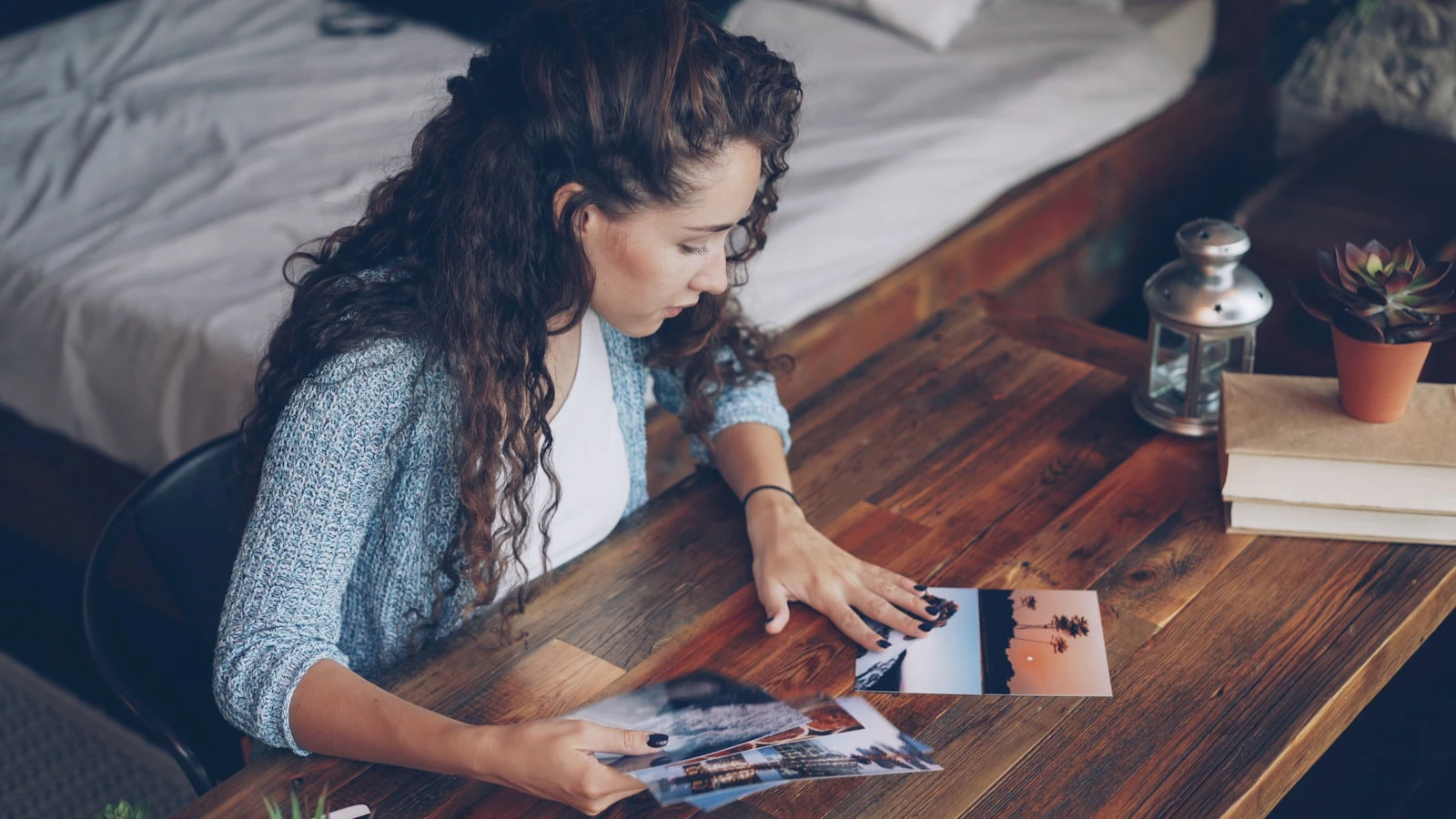 Photographer reviewing printed photographs laid out on a wooden desk before client delivery