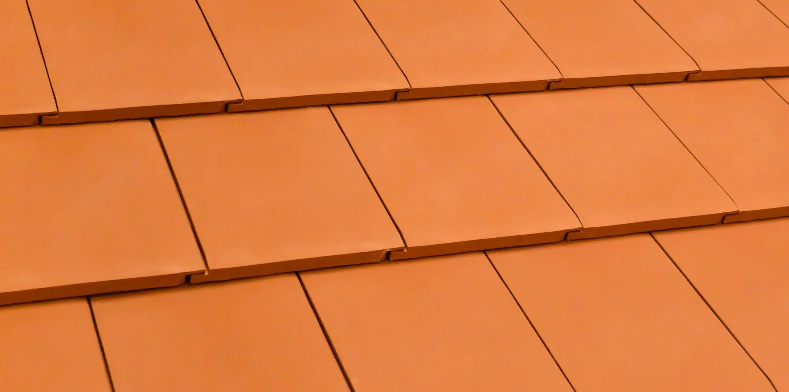 Close-up of terracotta roof tiles arranged in overlapping rows orange terracotta roof tiles overlapping rows