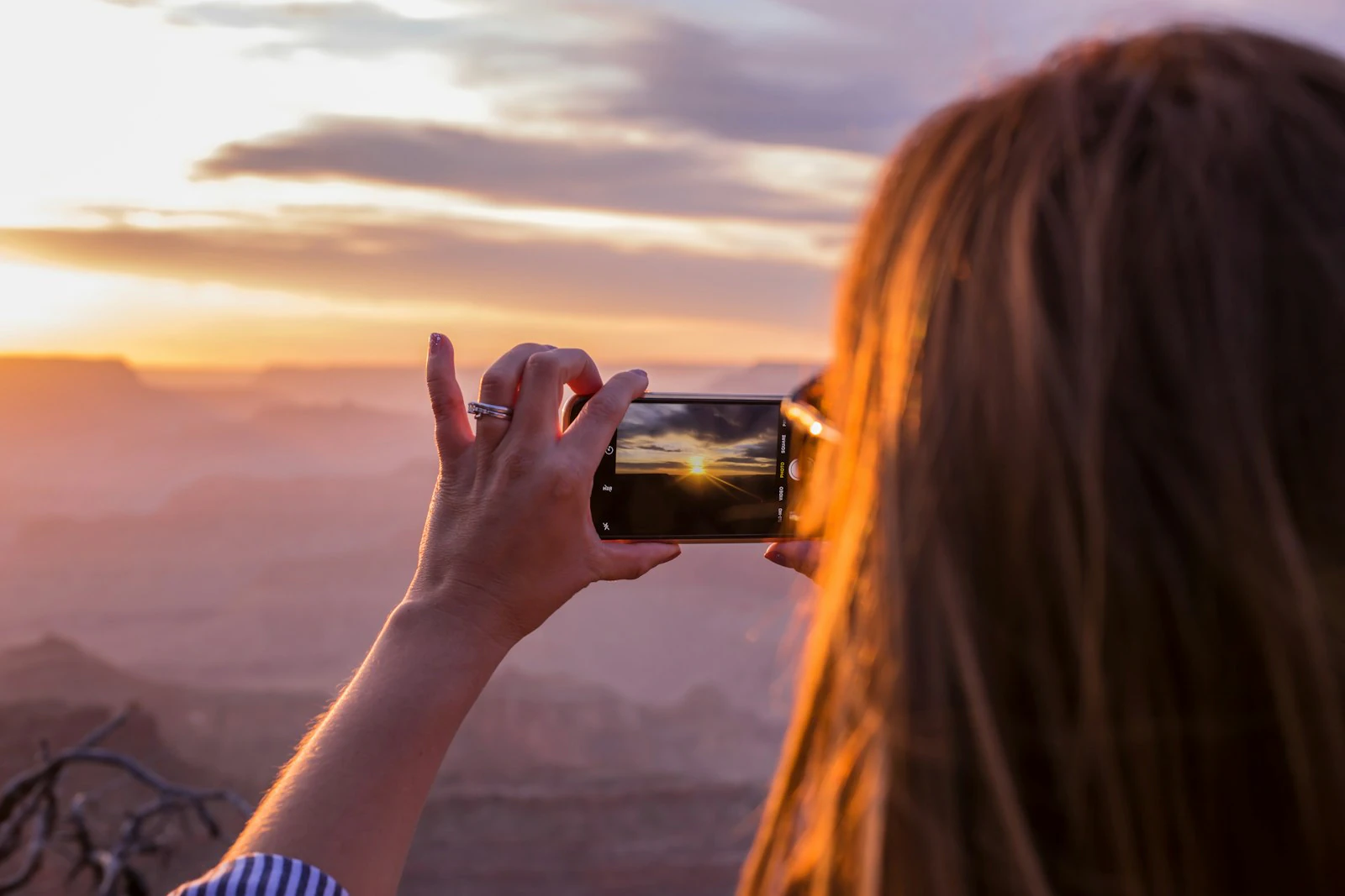 Photographer framing an orange sunset through her camera