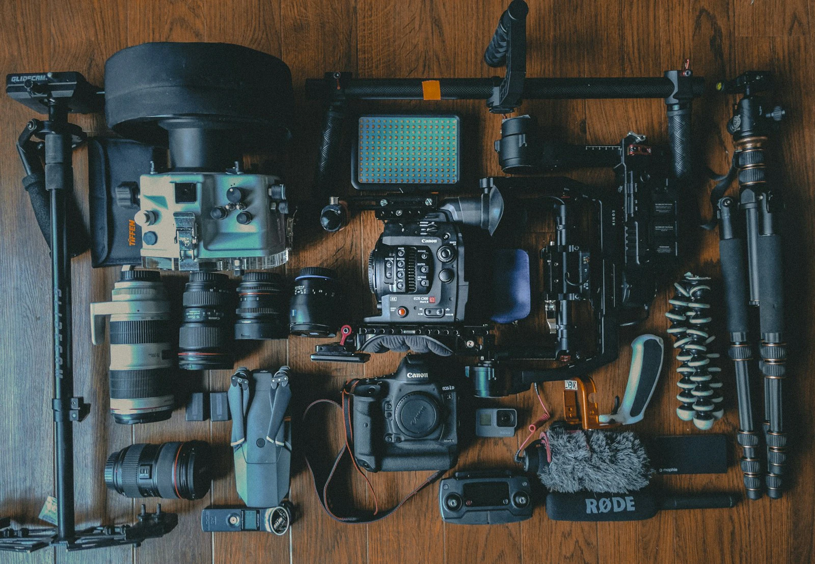Flat lay of photography gear: camera bodies, lenses, straps, and accessories packed around an open camera bag