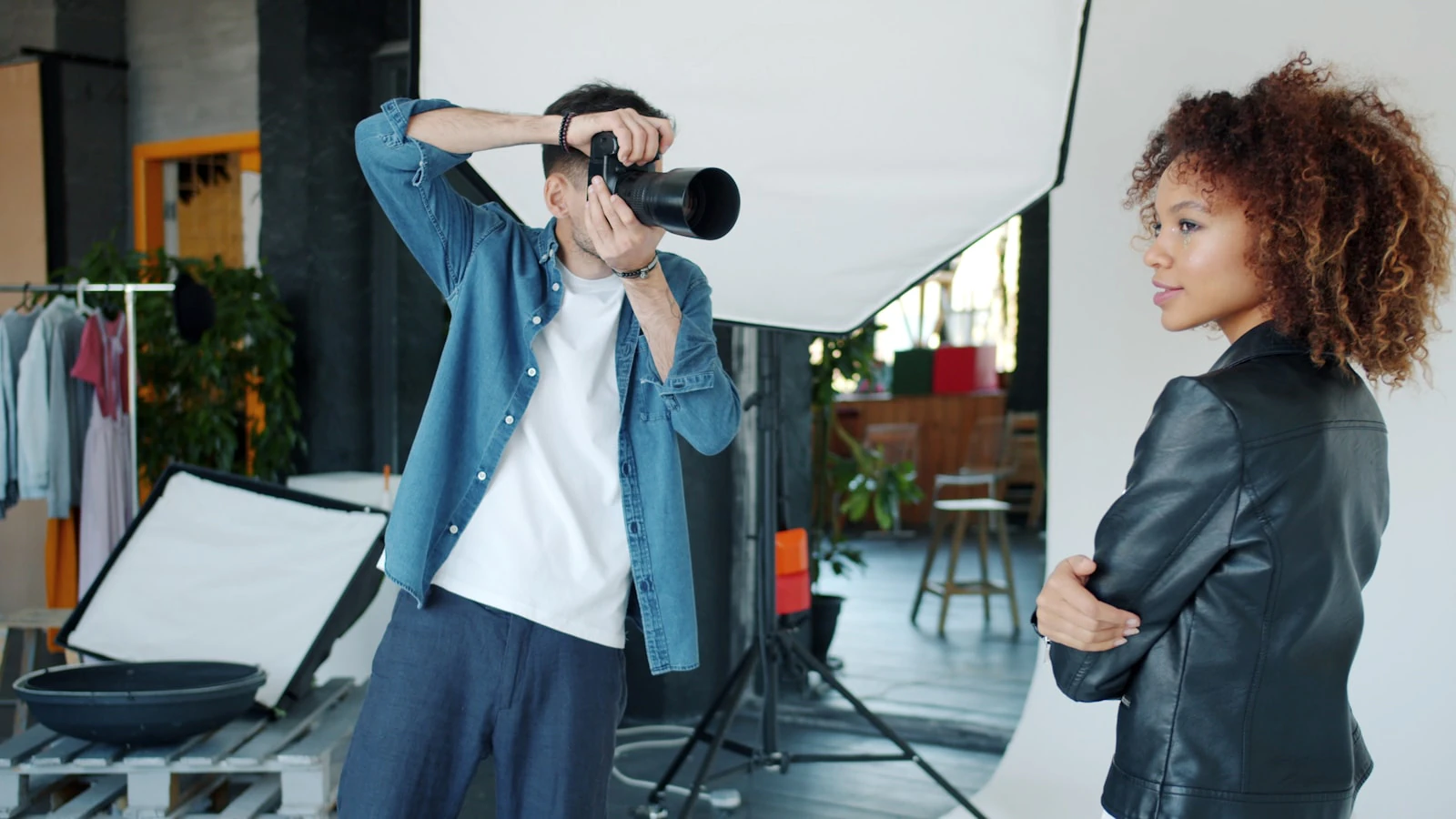 Photographer directing a model indoors while shooting with a professional camera