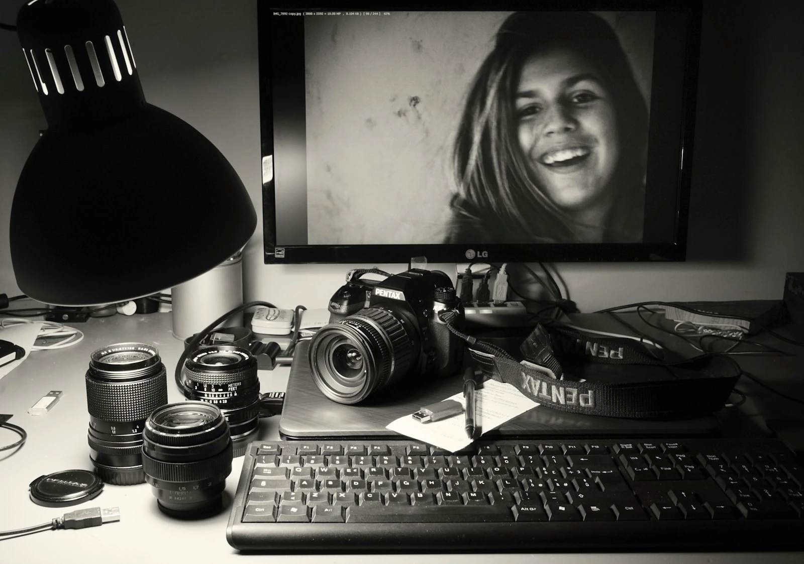 DSLR camera sitting beside a computer monitor on a photographer workspace ready for file transfer