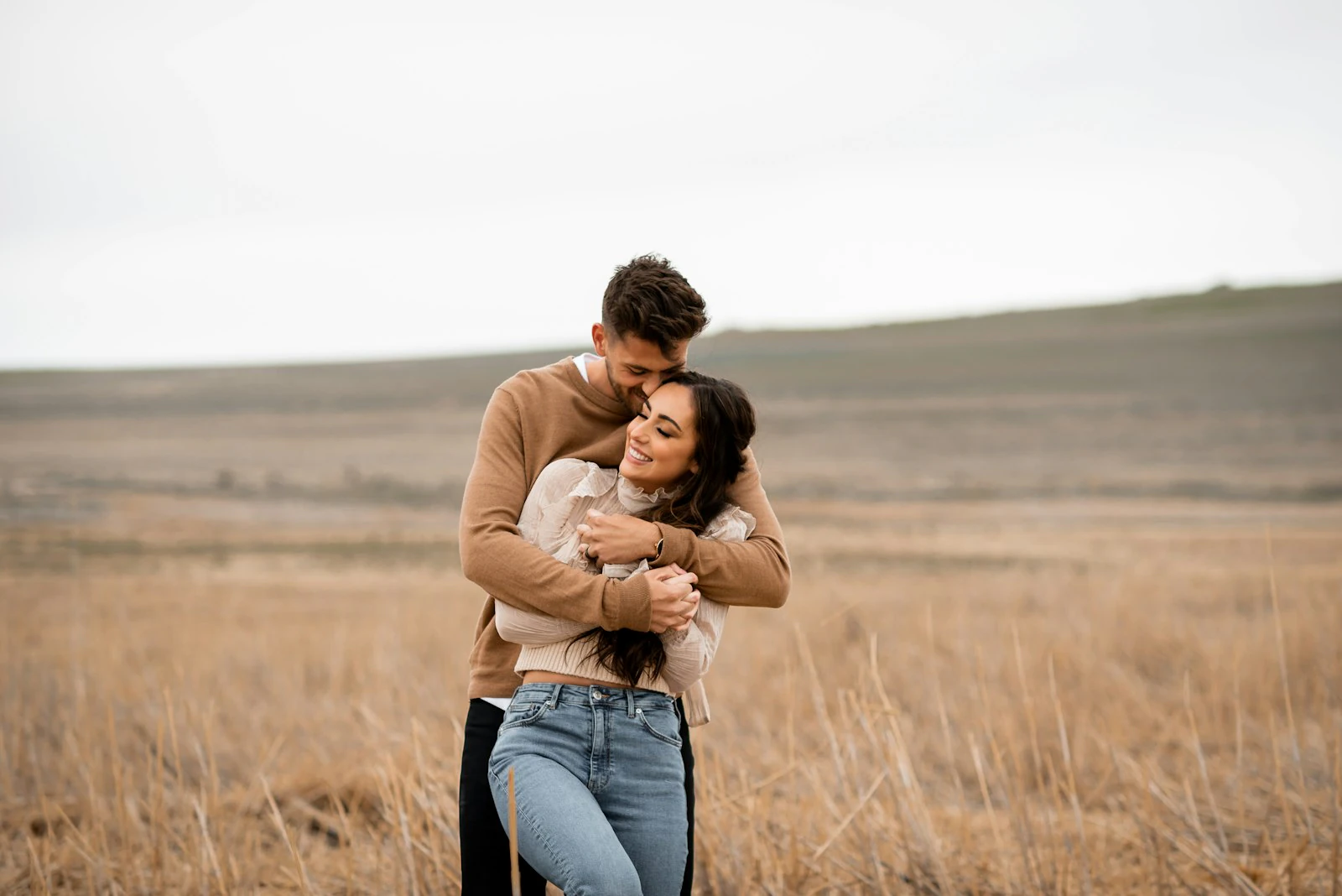 Couple embracing and laughing together in an open field during an outdoor photo session