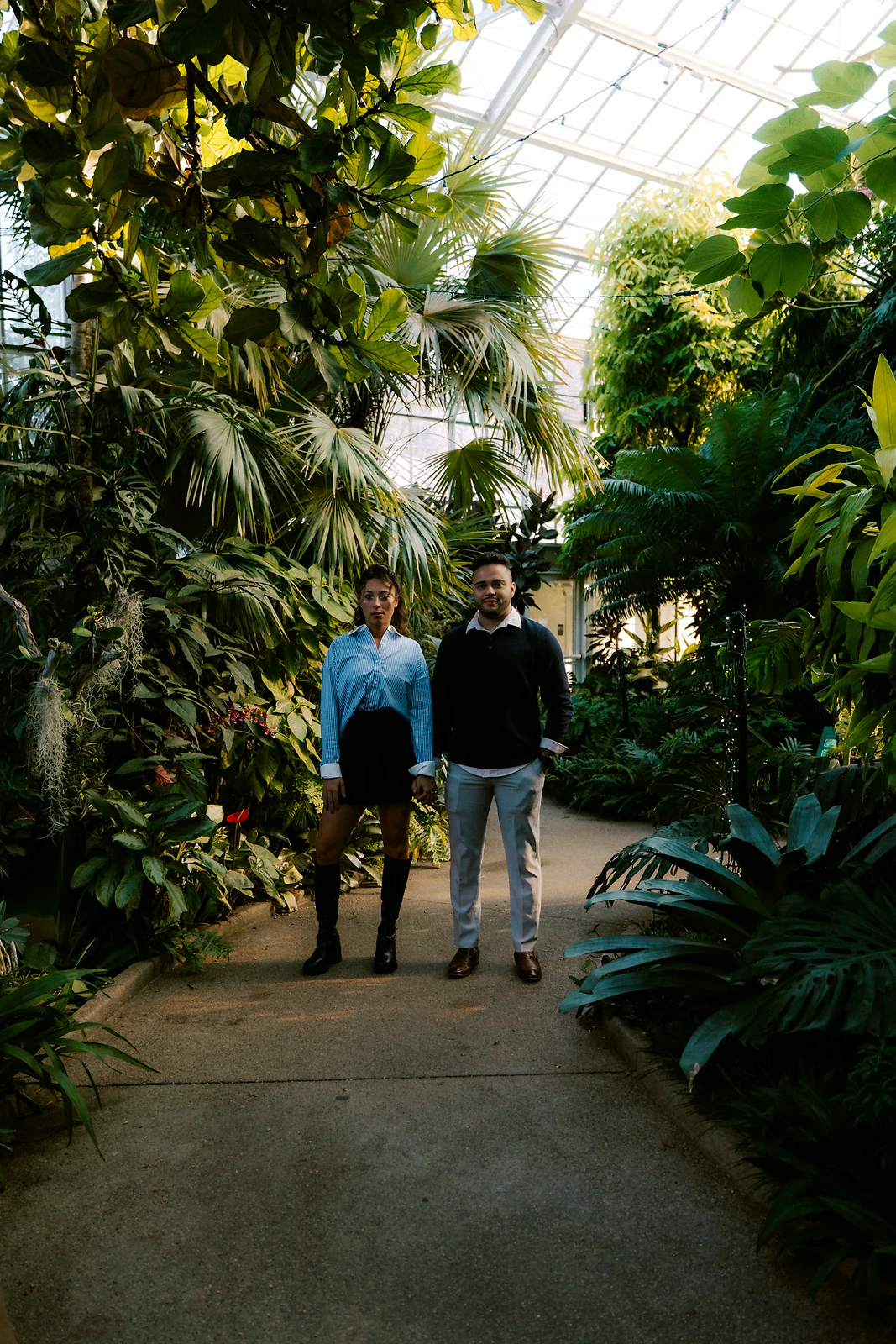 Couple standing among lush plants inside a botanical garden greenhouse