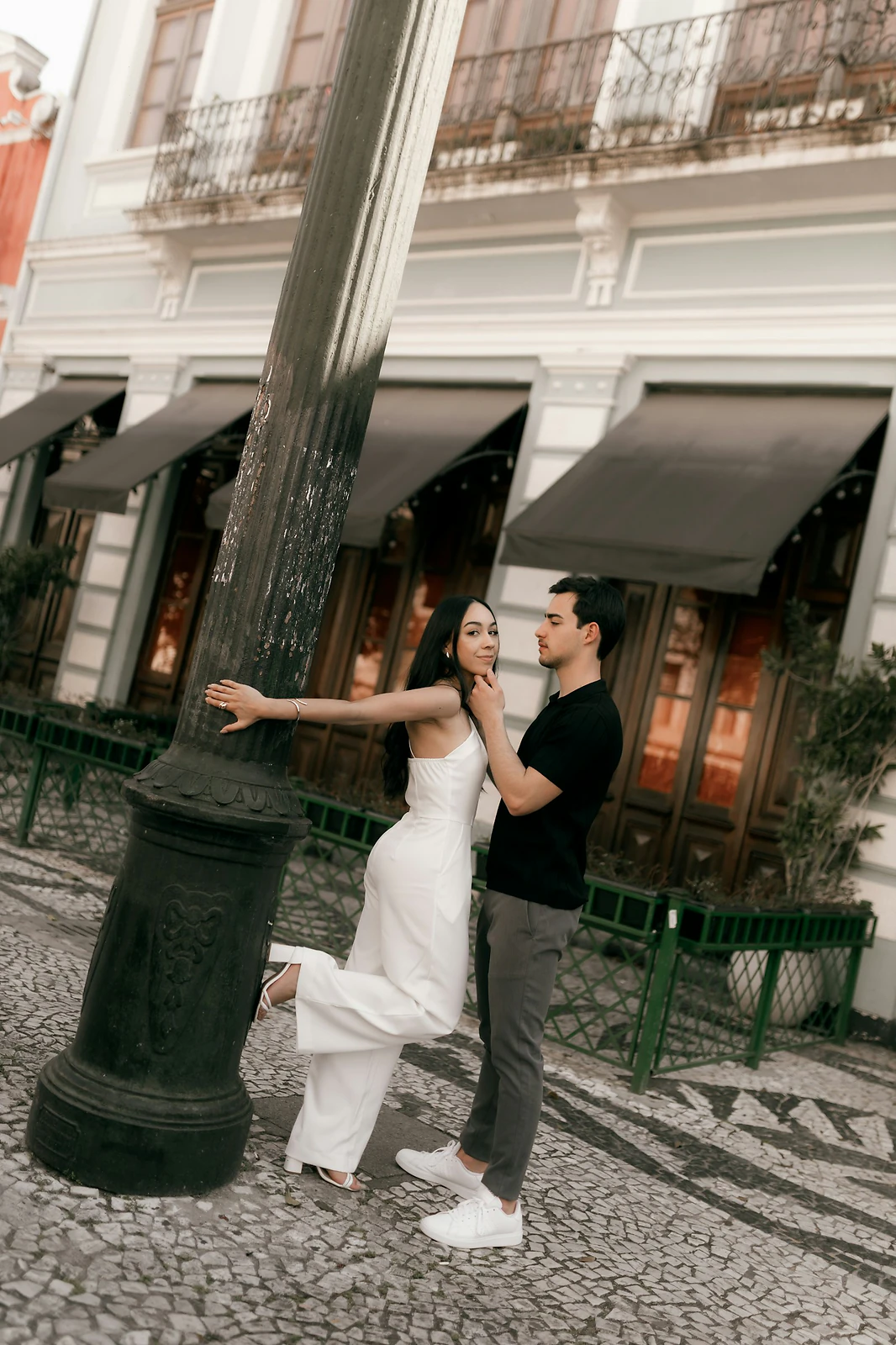 Engaged couple posing by a lamppost on a cobblestone street during their engagement session