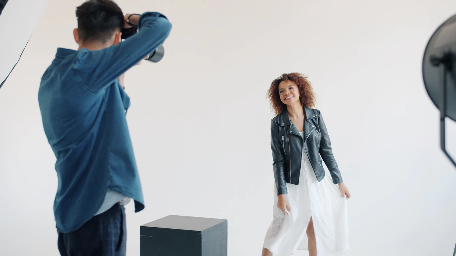 Model in a leather jacket posing against a white studio background with relaxed shoulders and an angled stance