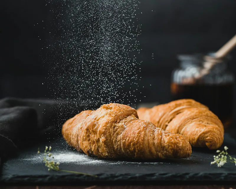 A butter croissant dusted with flour