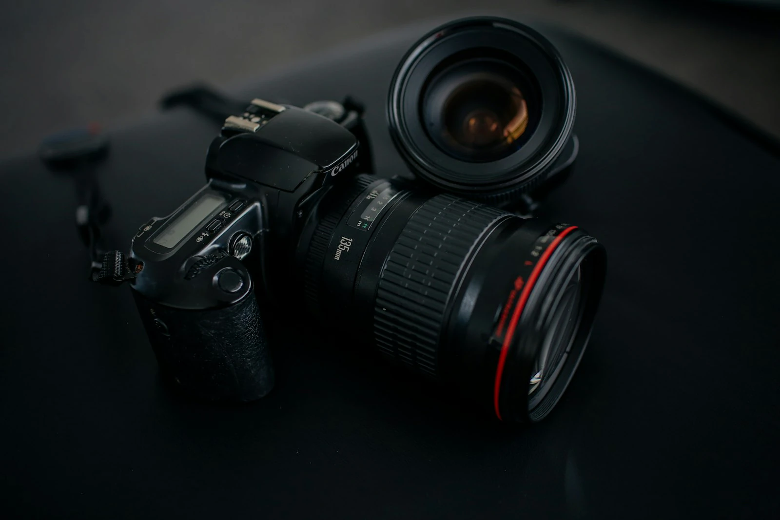Camera body next to a single prime lens on a dark background