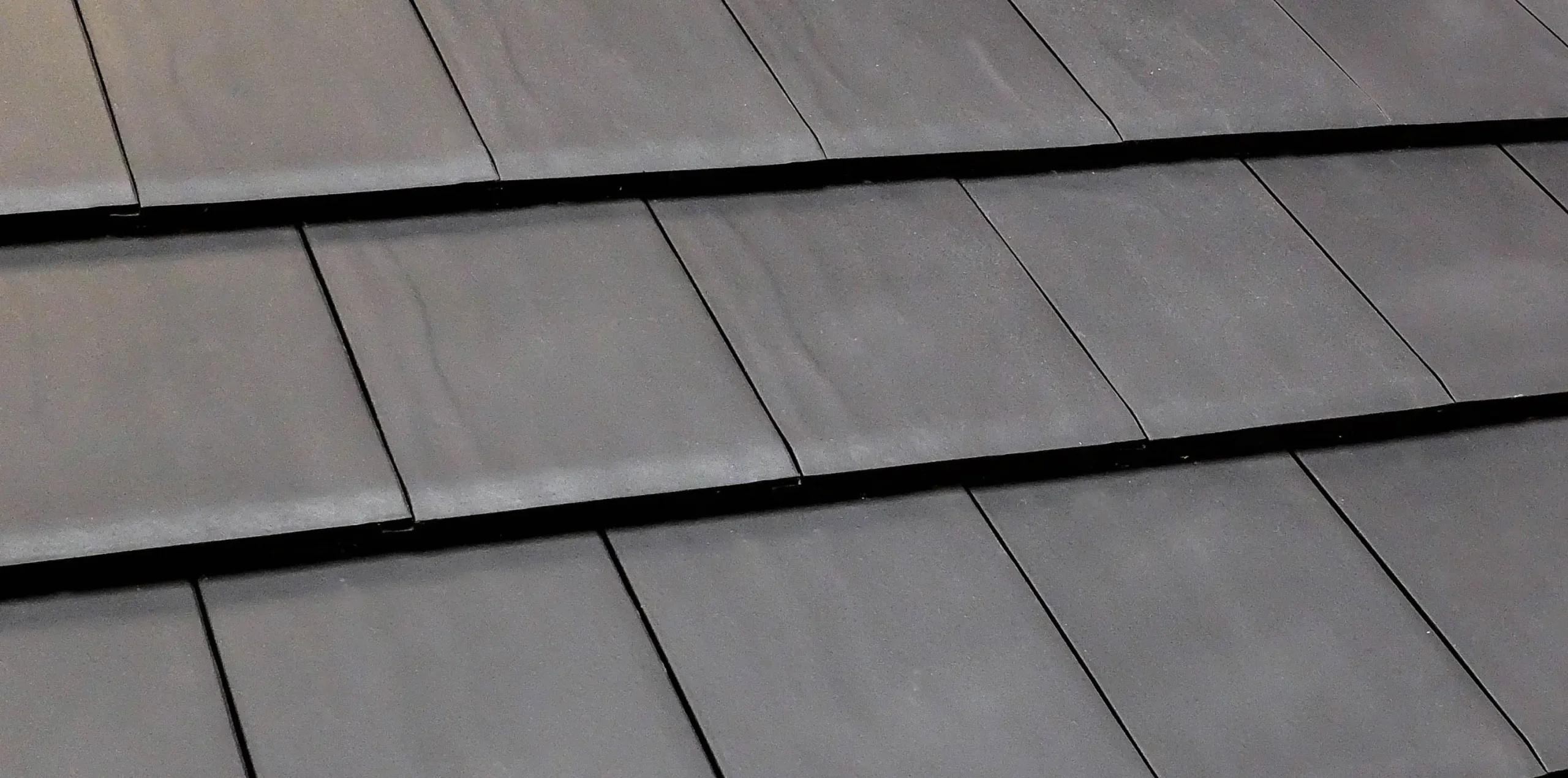 Close-up of black metal roof tiles overlapping in rows Black metal roof tiles overlapping rows